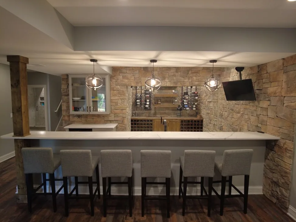 Finished basement bar with stone walls, seating, and pendant lights