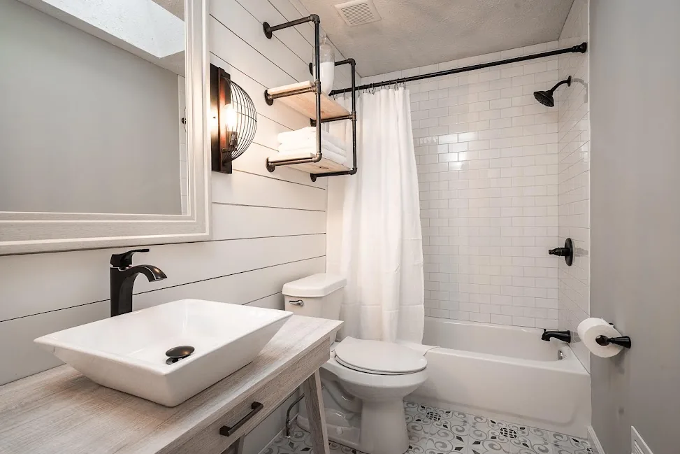 Finished bathroom with white tile, black fixtures, and a walk-in shower