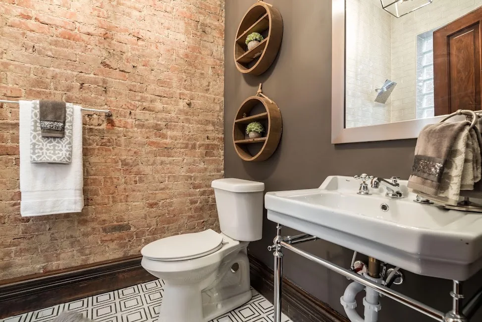 Finished bathroom with exposed brick, pedestal sink, and patterned tile floor