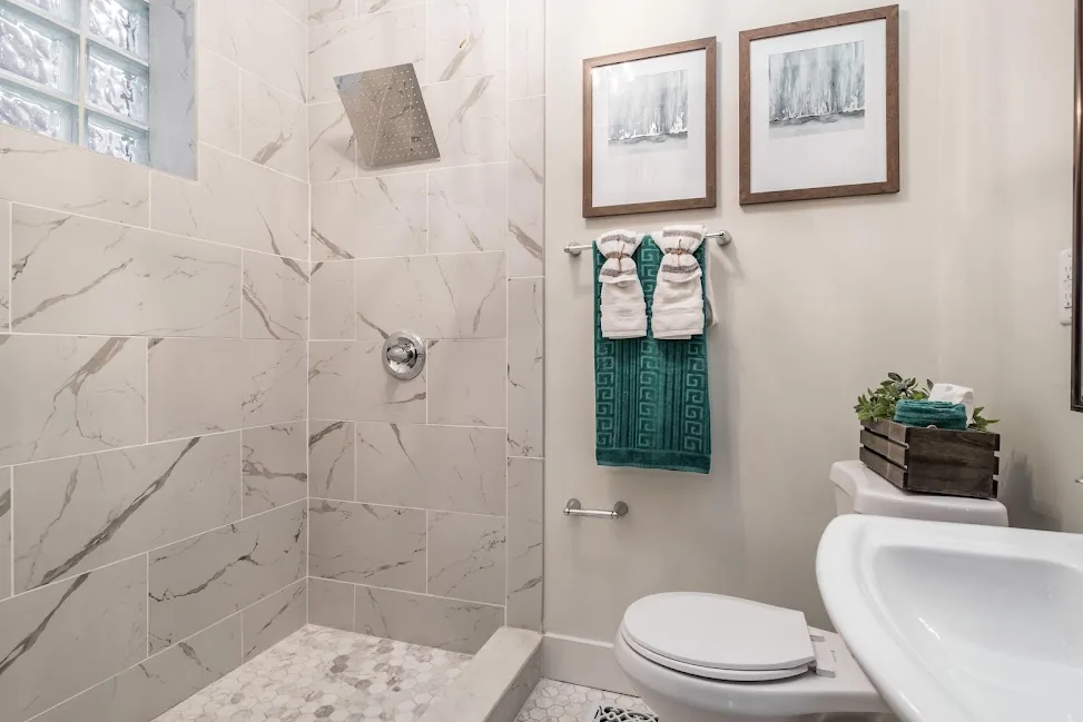 Finished bathroom with marble-look tile and a walk-in shower